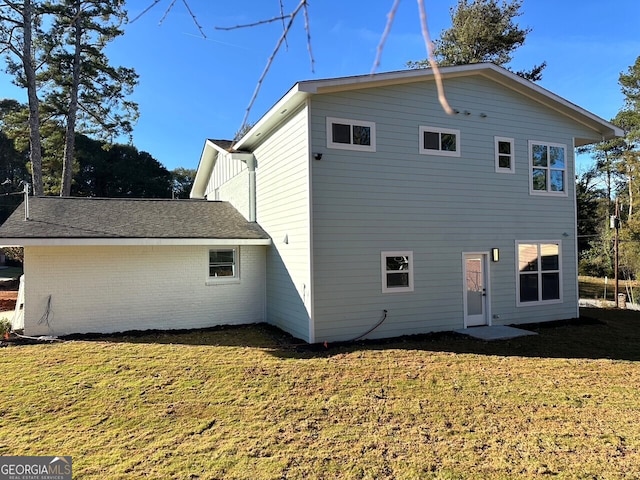 back of property with brick siding and a lawn