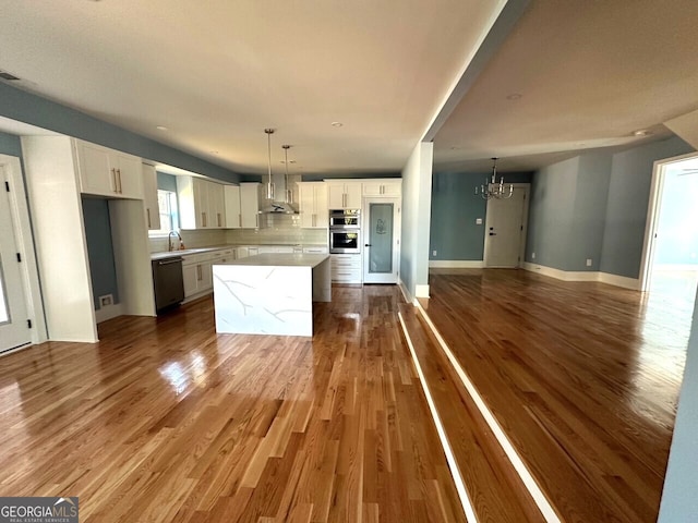 kitchen with a center island, an inviting chandelier, open floor plan, white cabinets, and dishwasher