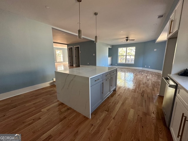 kitchen featuring decorative light fixtures, visible vents, open floor plan, light stone countertops, and dishwasher