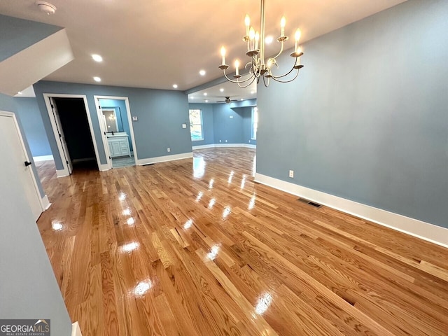 unfurnished living room with a notable chandelier, recessed lighting, wood finished floors, visible vents, and baseboards