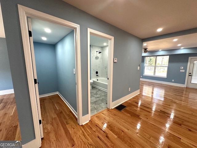 hallway featuring light wood-type flooring, visible vents, and baseboards