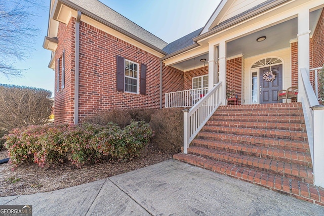 entrance to property with covered porch and brick siding