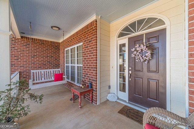 entrance to property with covered porch and brick siding