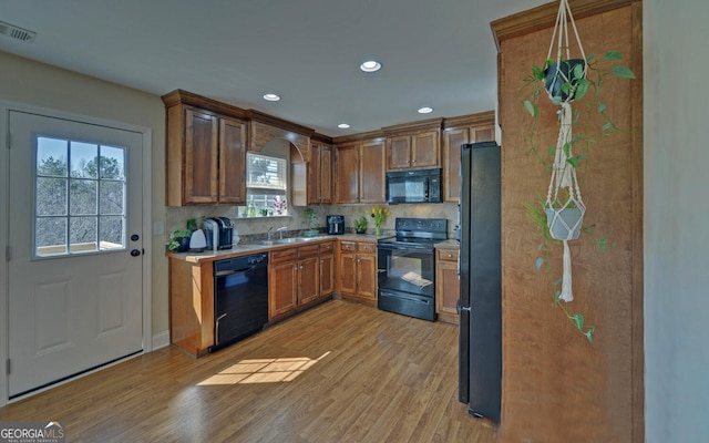 kitchen with light wood-style flooring, visible vents, light countertops, black appliances, and brown cabinetry