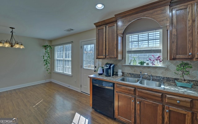 kitchen featuring black dishwasher, backsplash, a sink, and visible vents