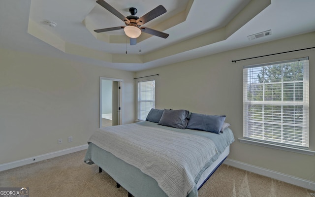 bedroom featuring visible vents, multiple windows, a tray ceiling, and baseboards