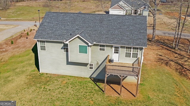 rear view of property featuring a lawn and roof with shingles