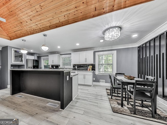 kitchen featuring a kitchen island, white cabinetry, light countertops, stainless steel fridge with ice dispenser, and pendant lighting