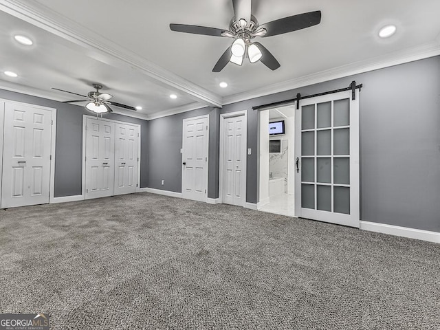 unfurnished bedroom with carpet floors, a barn door, and ornamental molding