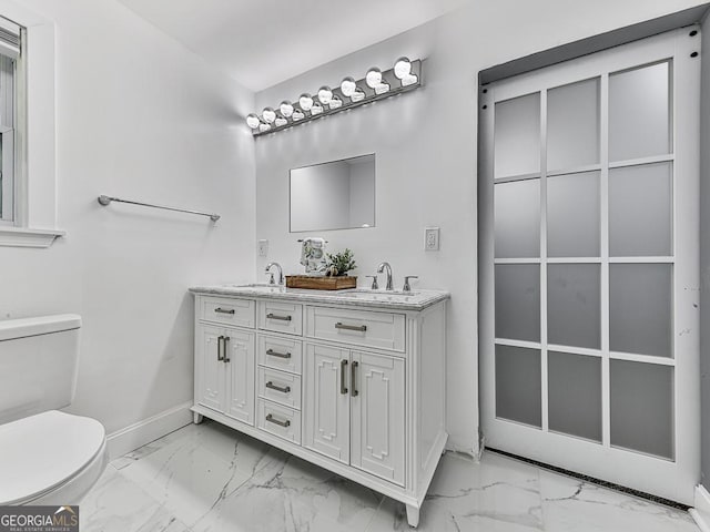 full bathroom with marble finish floor, baseboards, toilet, and double vanity