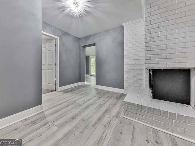 unfurnished living room featuring a brick fireplace, light wood-style flooring, and baseboards