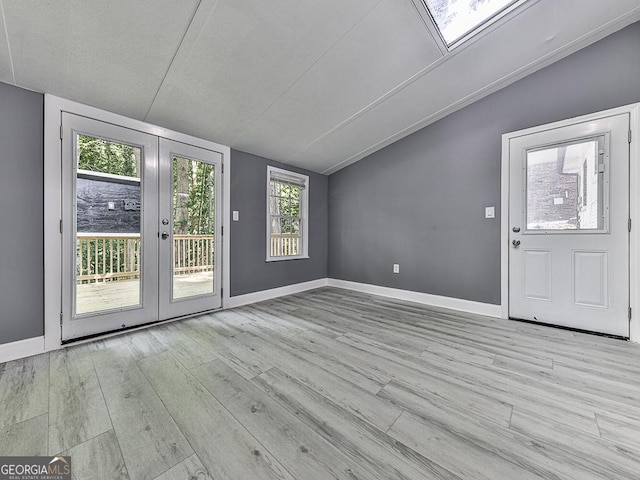 interior space featuring french doors, baseboards, vaulted ceiling, and light wood finished floors