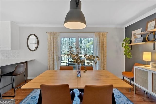 dining room featuring baseboards, wood finished floors, and crown molding