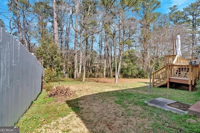 view of yard featuring a deck, stairway, and fence