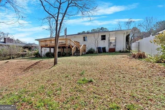 rear view of property with a deck, a lawn, and fence