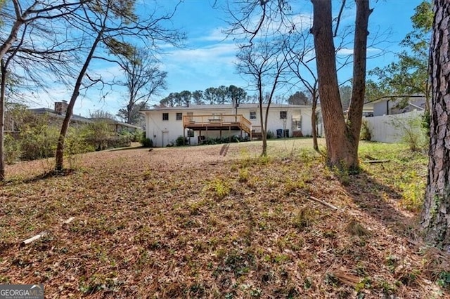 rear view of property featuring fence and a deck