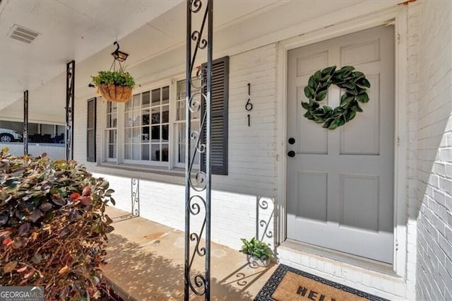 property entrance with visible vents and brick siding