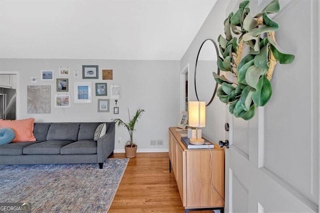 living area featuring light wood finished floors, visible vents, and baseboards