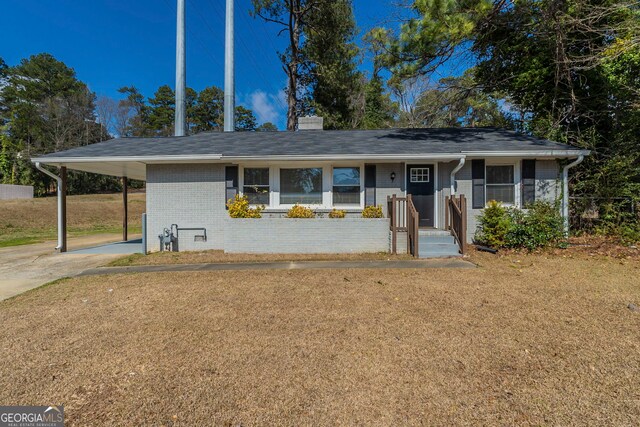 ranch-style house with driveway, brick siding, a chimney, an attached carport, and a front yard