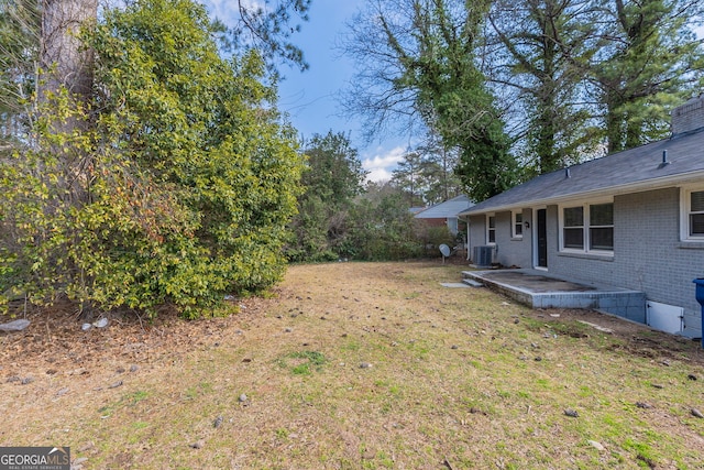 view of yard with central AC and a patio