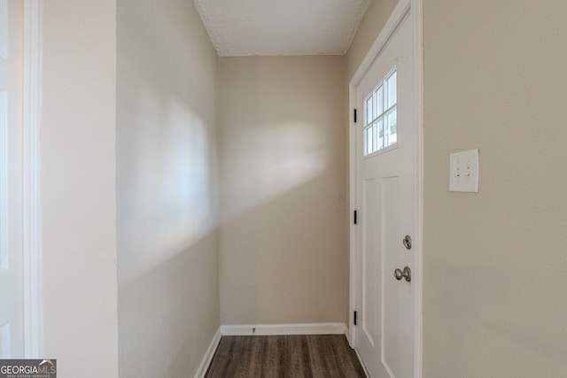 doorway with baseboards and dark wood-style flooring