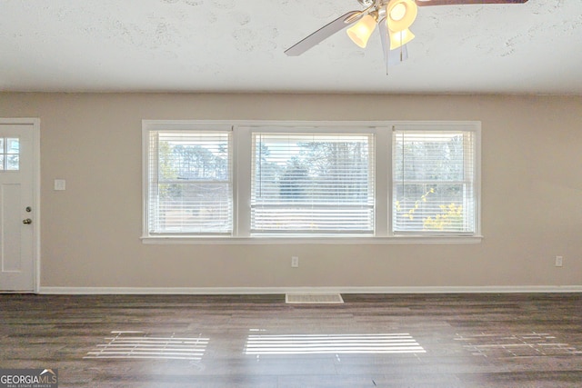 interior space with dark wood-style floors, baseboards, visible vents, and a ceiling fan