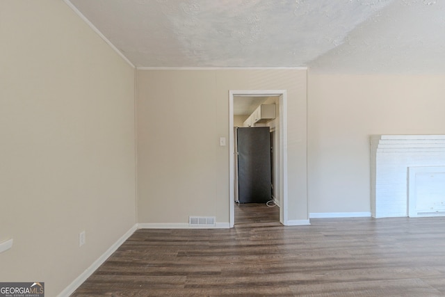 empty room with wood finished floors, visible vents, and baseboards