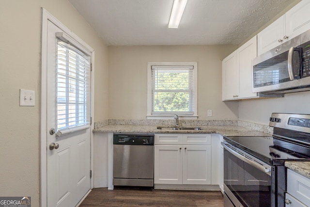 kitchen featuring white cabinetry, appliances with stainless steel finishes, light stone counters, and a sink