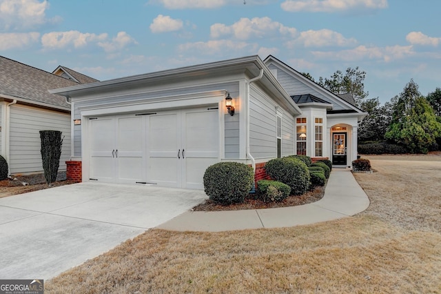 view of front of house with an attached garage, concrete driveway, and a front yard