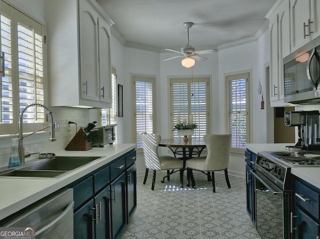 kitchen with a sink, white cabinetry, light countertops, appliances with stainless steel finishes, and crown molding