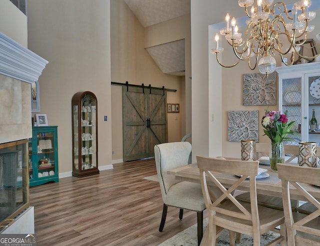 dining area with a barn door, a towering ceiling, baseboards, and wood finished floors