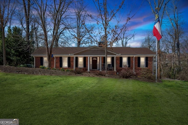 ranch-style house featuring a chimney, a front lawn, and brick siding