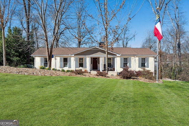 ranch-style home featuring brick siding, a front lawn, and a chimney