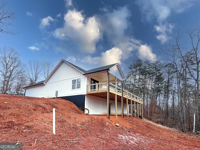 view of property exterior featuring a shingled roof and a wooden deck