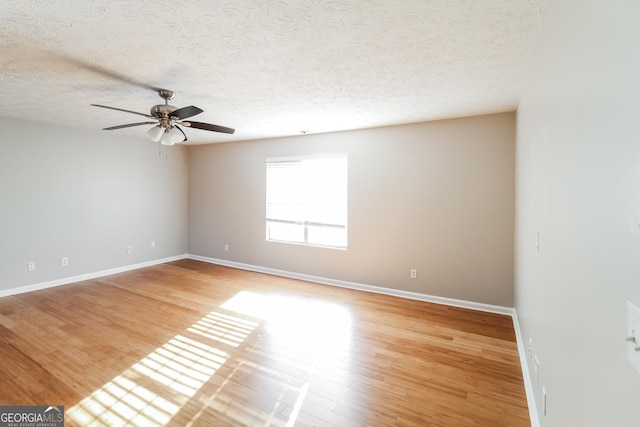 spare room with ceiling fan, a textured ceiling, baseboards, and wood finished floors