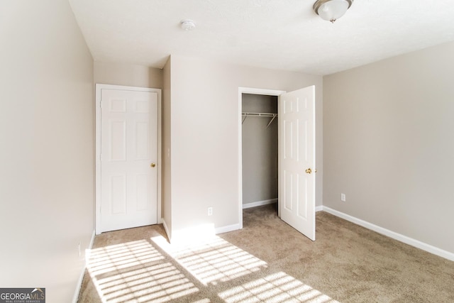 unfurnished bedroom featuring light carpet, a closet, and baseboards