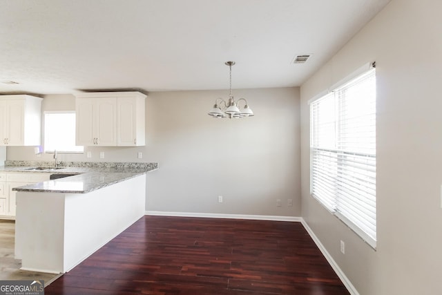 kitchen with a peninsula, dark wood finished floors, decorative light fixtures, and white cabinets