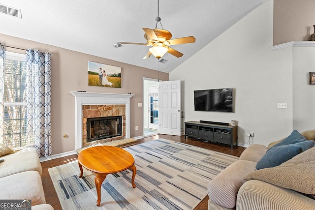 living room with baseboards, visible vents, a ceiling fan, a tiled fireplace, and wood finished floors