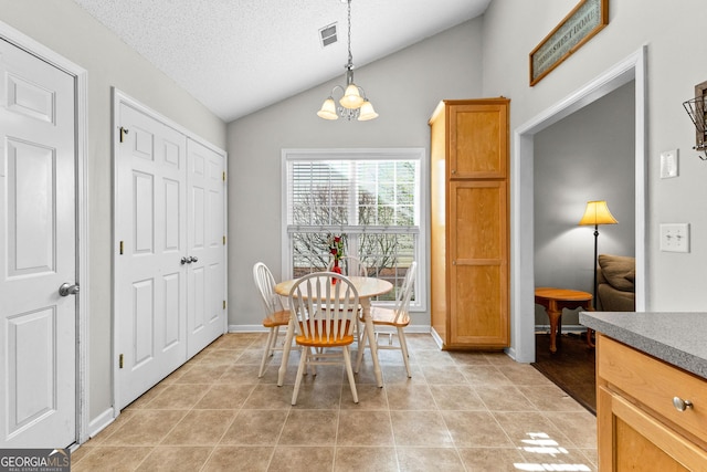 dining area featuring light tile patterned floors, visible vents, vaulted ceiling, a textured ceiling, and baseboards