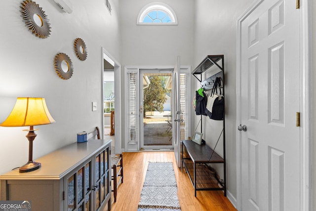 entrance foyer with light wood finished floors, a high ceiling, and baseboards