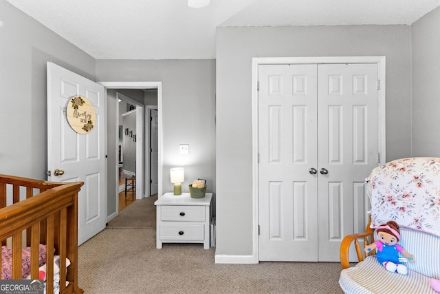 bedroom featuring baseboards, a closet, and light colored carpet