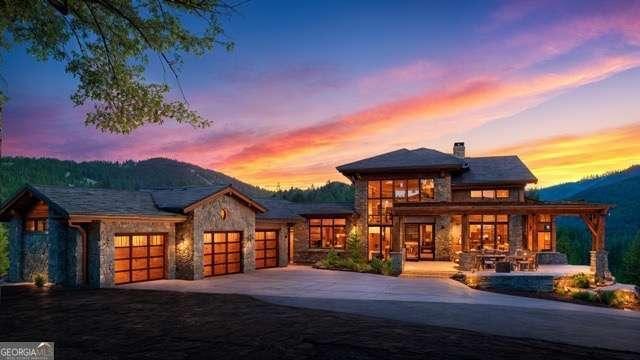 view of front of home featuring a garage, stone siding, a mountain view, and concrete driveway