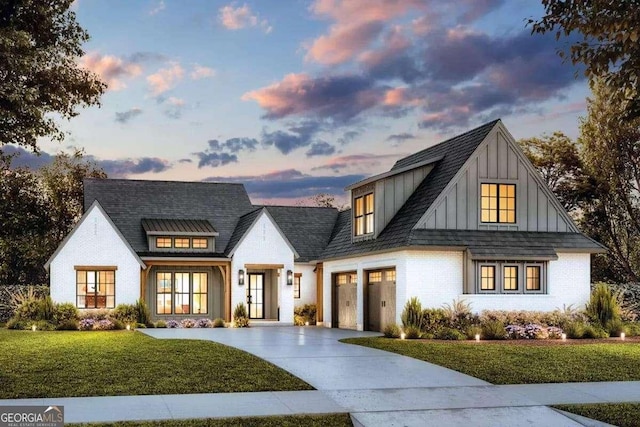 modern farmhouse featuring brick siding, a yard, concrete driveway, board and batten siding, and a garage