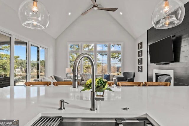 kitchen featuring hanging light fixtures, a large fireplace, high vaulted ceiling, and open floor plan