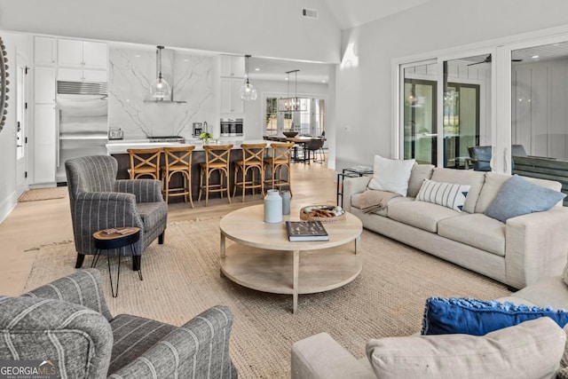 living area with light wood-type flooring, visible vents, vaulted ceiling, and recessed lighting