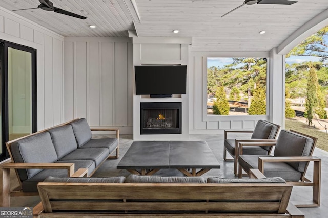 exterior space with wood ceiling, ceiling fan, recessed lighting, and a lit fireplace