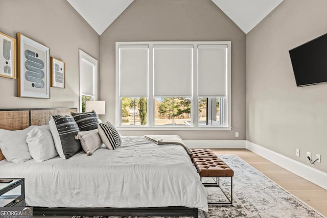 bedroom with lofted ceiling, light wood finished floors, and baseboards