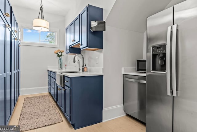 kitchen with blue cabinets, stainless steel appliances, light countertops, and hanging light fixtures