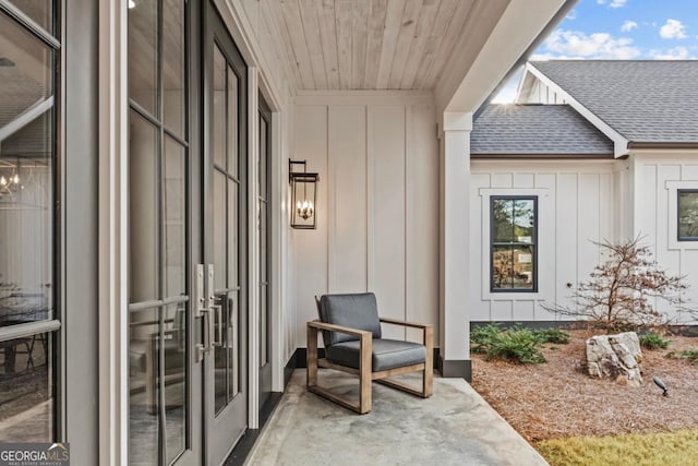 view of exterior entry with roof with shingles, french doors, and board and batten siding