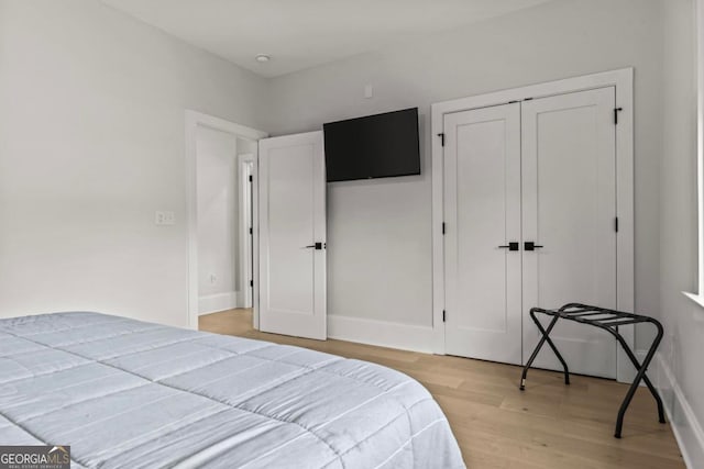 bedroom with a closet, light wood-type flooring, and baseboards